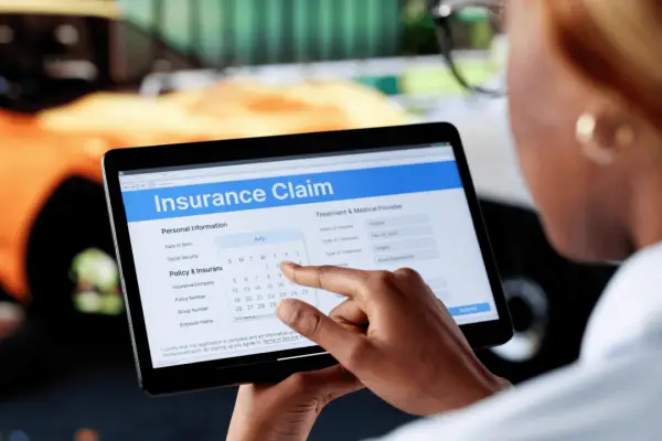 Person selecting a date on an insurance claim form on a tablet after a car accident, illustrating when to file insurance claim